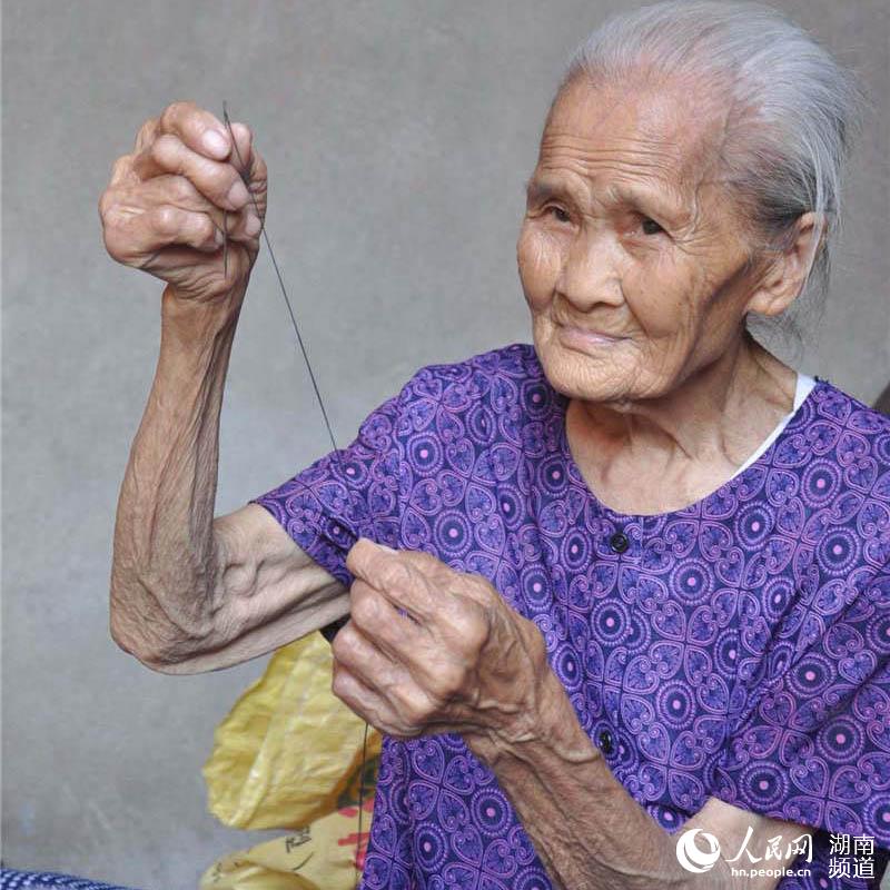 湖南麻阳县105岁的滕友莲老人正在穿针。
