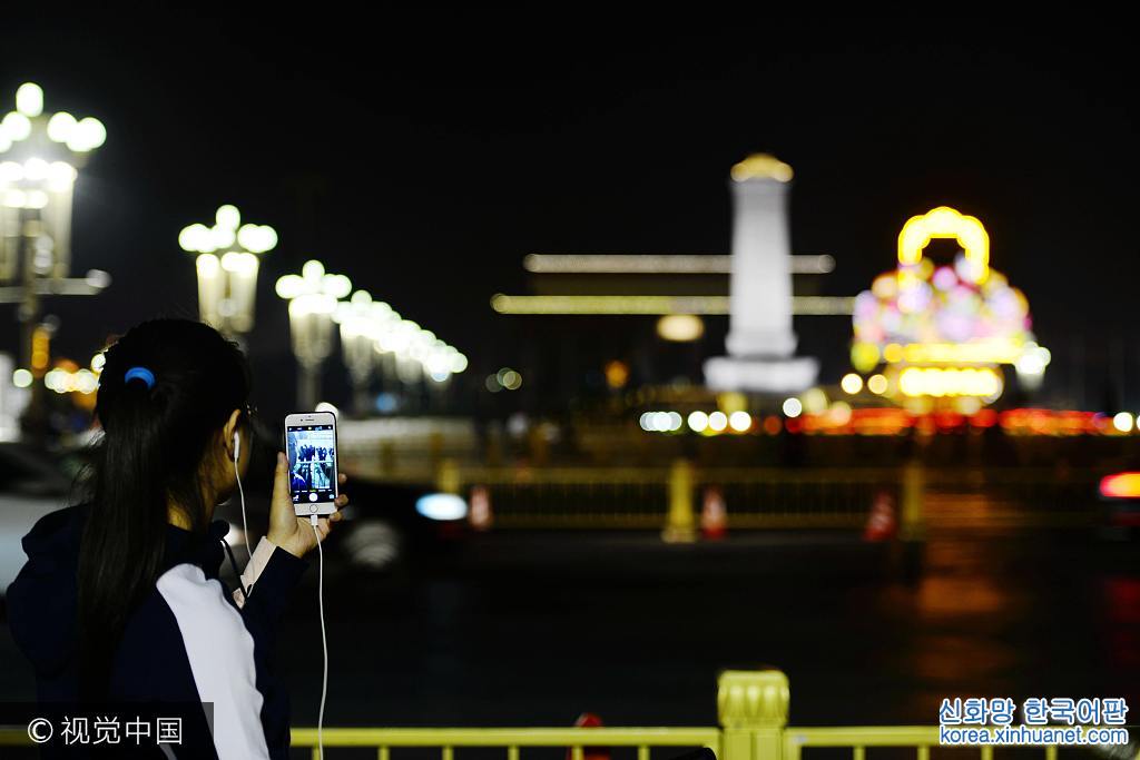 ***_***2017年9月27日晚，北京，天安门广场，国庆“大花蓝”夜景首次绽放。一位市民隔着长安街用手机在拍摄大花蓝夜景。